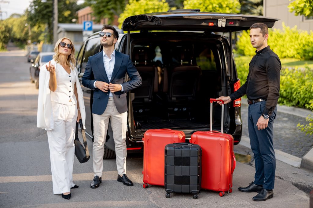 Business couple near minivan taxi with a suitcases and chauffeur